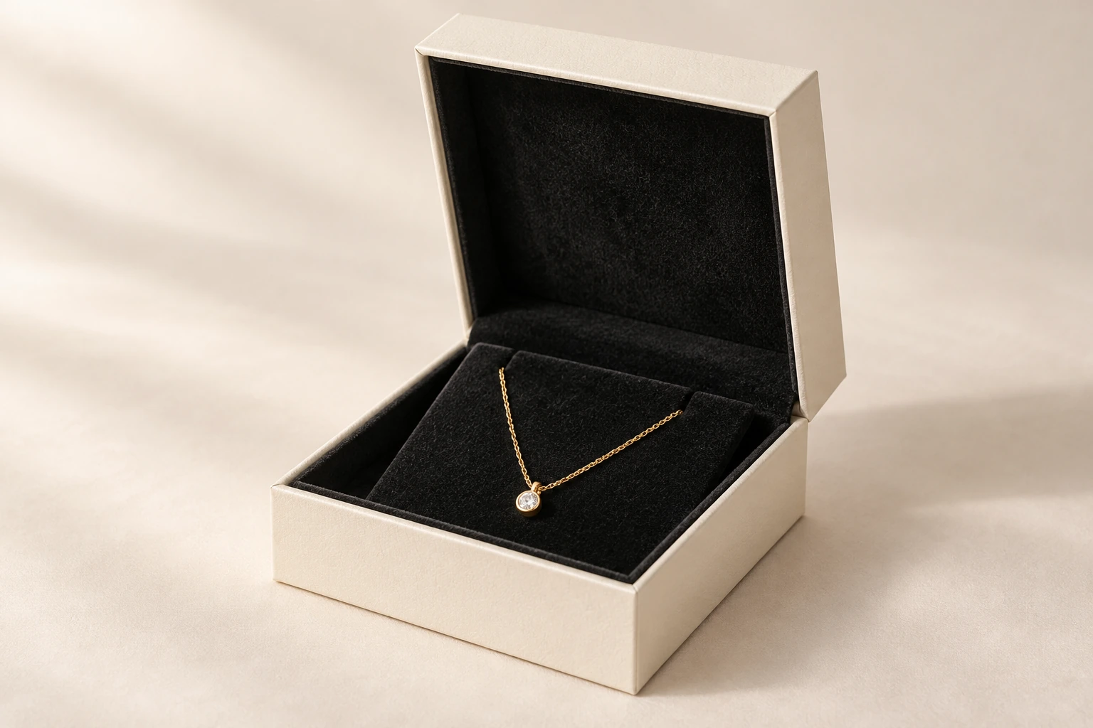 Ivory jewellery box with black flocked lining and a gold pendant